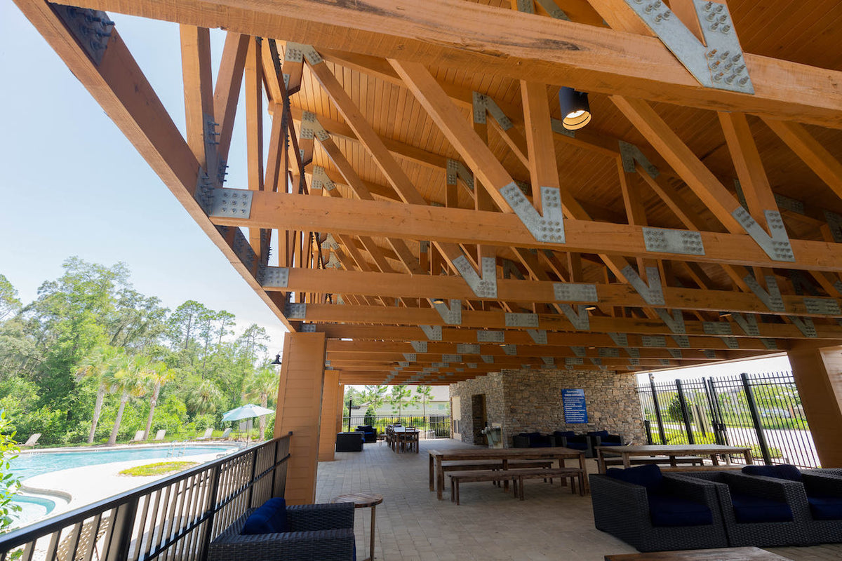 Under the pavilion's roof: timber trusses with galvanized plates over the lounge, the pool beyond