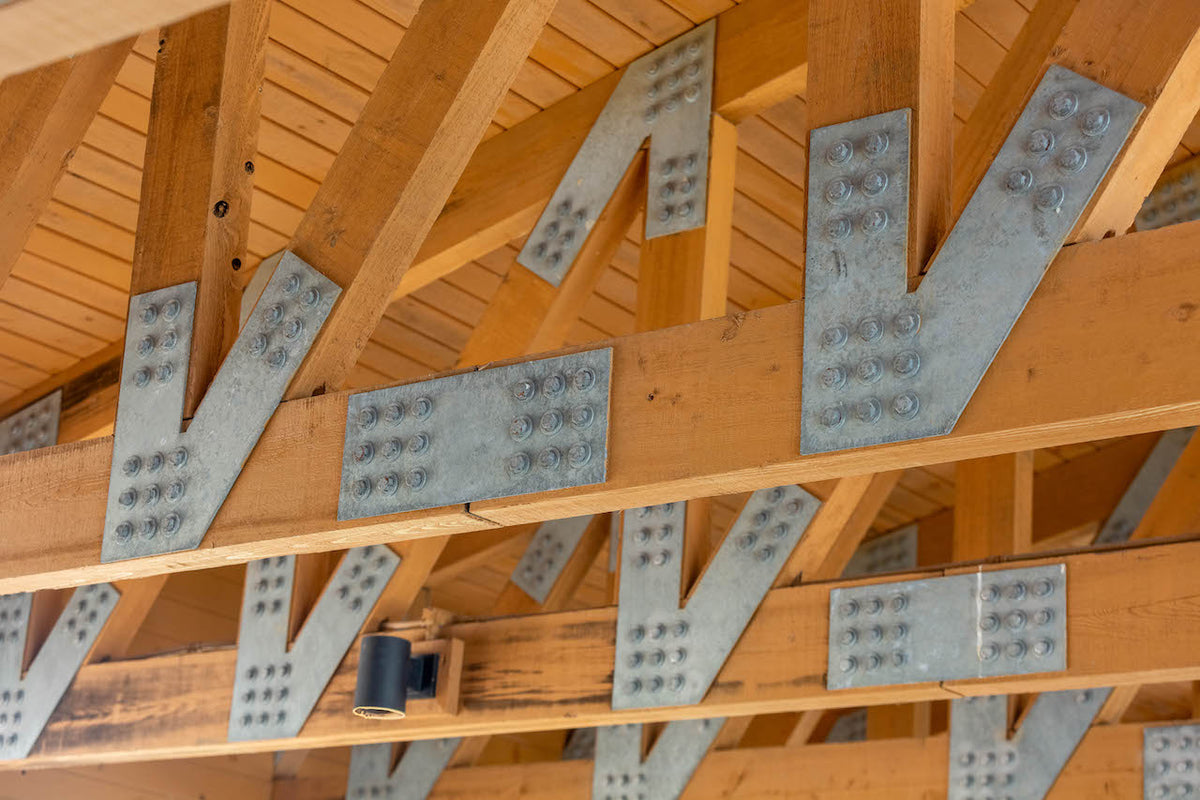 Rows of galvanized V-shaped and straight plates bolted to the trusses