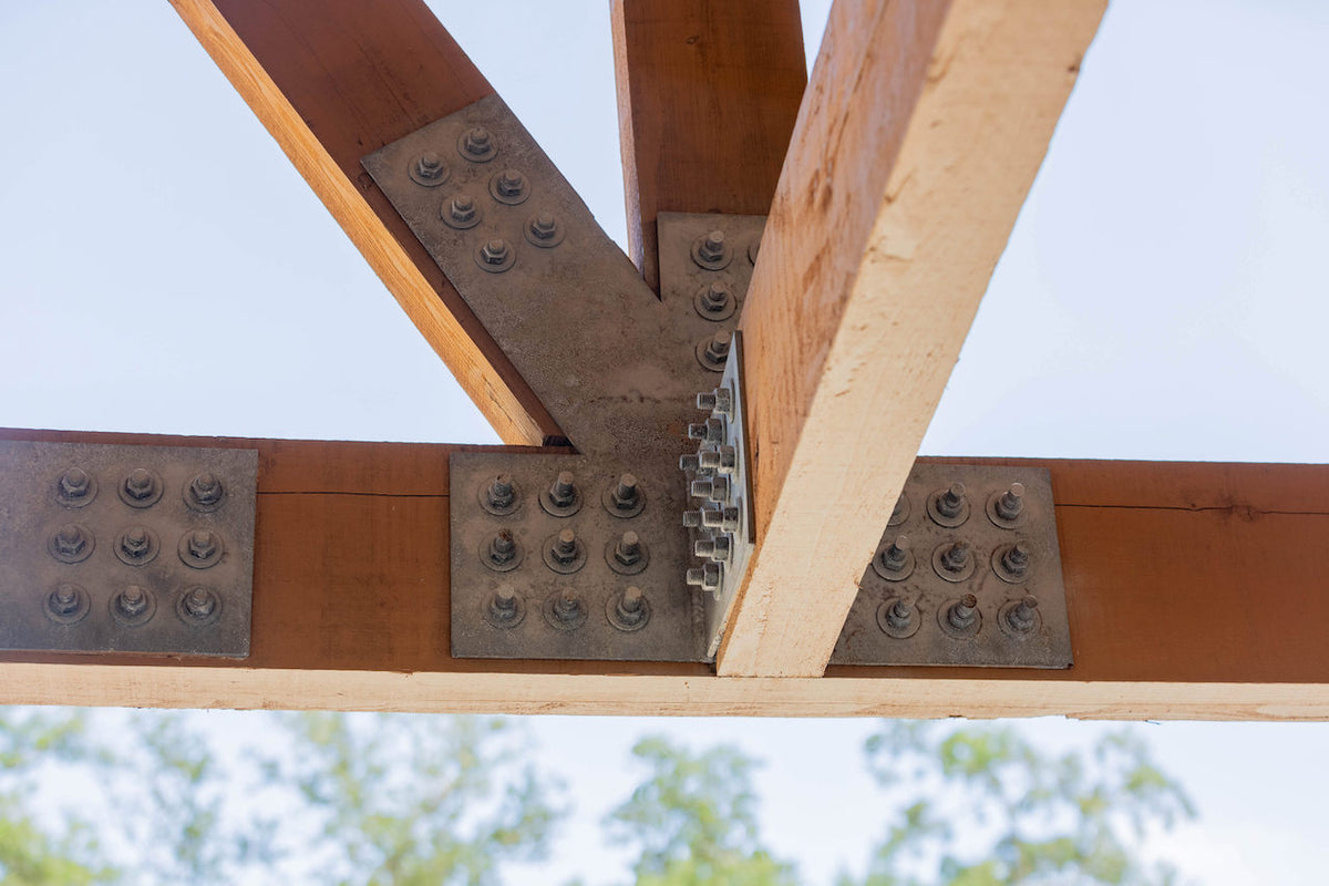 Galvanized plates joining three timbers of a truss, seen against the sky