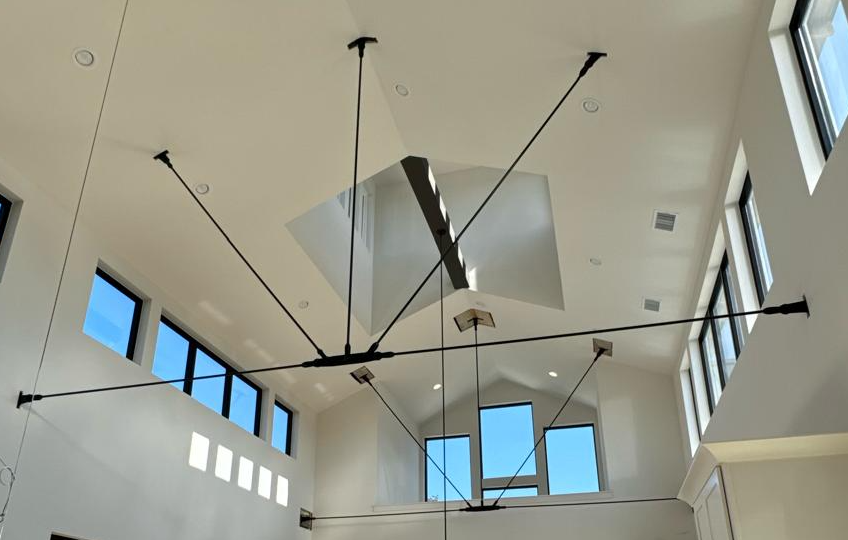 Black steel tie rods radiating from center plates across a tall vaulted ceiling with clerestory windows